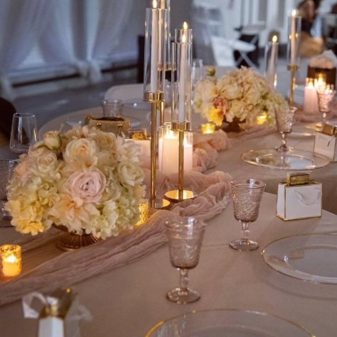 Elegant wedding reception table with blush and ivory floral arrangements, candlelight, and gold accents designed by a wedding planner.